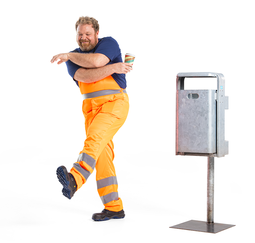 Mike der Müllexperte in orangefarbener Arbeitskleidung, der mit einen To-go-Becher in der Hand neben einem Mülleimer tanzt.